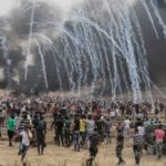 Palestinian protesters flee from incoming teargas canisters during clashes with Israeli forces along the border with the Gaza Strip east of Gaza City on May 4, 2018. 