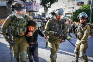 Israeli soldiers arrest a Palestinian boy as Jew-Israelis tour in the West Bank city of Hebron, during the Jewish holiday of Sukkot, September 23, 2021.