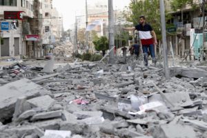 A man inspects the rubble of destroyed commercial building and Gaza health care clinic following an Israeli airstrike.