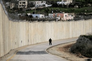 A man walks along a road by Israel's controversial separation barrier between the occupied West Bank village of Nazlat Issa (left) and the Arab-Israeli town of Baqa al-Gharbiya (right) in northern Israel. 