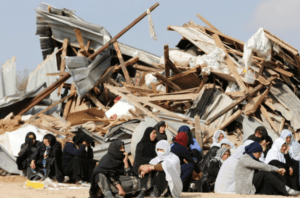 Bedouin women sit next to the ruins of their dwellings demolished by Israeli bulldozers in Umm Al-Hiran
