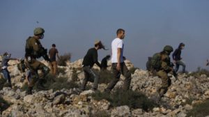 Israeli soldiers and settlers confront Palestinians during a protest against the expansion of Jewish settlements near the West Bank town of Salfit, Monday, Nov. 30, 2020.