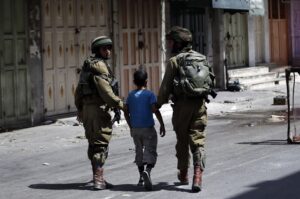 Israeli soldiers arrest a young Palestinian boy following clashes in the center of the West Bank town of Hebron, on June 20, 2014.