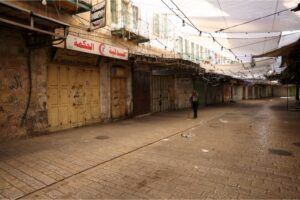 A man walks next to shuttered shops in the occupied West Bank city of Hebron