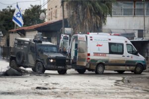 An Israeli military vehicle blocks an ambulance during a raid in Jenin