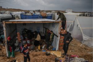 Palestinian families take refuge in the logistics base of UNRWA and in the makeshift tents they have built around the storage as they struggle with cold weather in Rafah, Gaza on 13 December 2023.