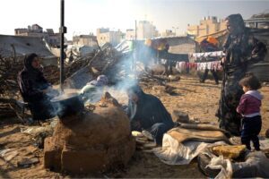 Palestinians displaced by the Israeli bombardment of the Gaza Strip cook at the makeshift tent camp in al-Mawasi