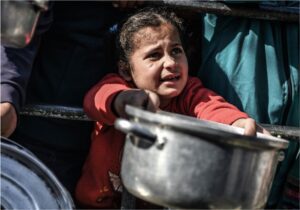 An eight-year-old child waits her turn to receive food in Rafah, in the southern Gaza Strip