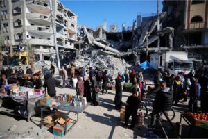 Palestinians shop at the market established between the destroyed buildings in the Israeli attacks at Nuseirat refugee camp in Deir al-Balah, Friday