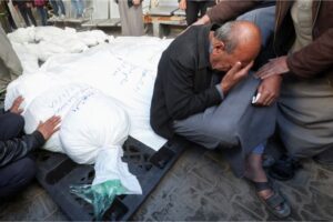A mourner grieves next to the bodies of Palestinians killed in an Israeli strike in Rafah in the southern Gaza Strip, January 18, 2024