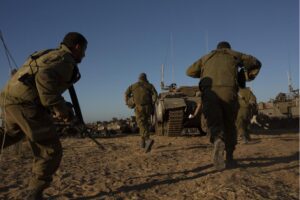 Israeli soldiers run for cover under armored vehicles near the Gaza border as a siren warns of incoming rockets.