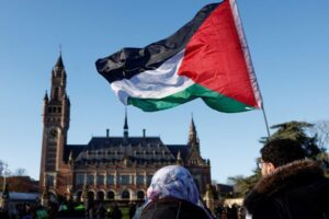 Protesters hold a Palestinian flag as they gather outside the International Court of Justice (ICJ). January 26, 2024