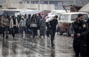 Palestinian people walk under the rain at a makeshift camp housing displaced people in Rafah earlier this month.