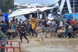 Palestinians carry bags of flour they grabbed from an aid truck near an Israeli checkpoint in Gaza City, January 27, 2024