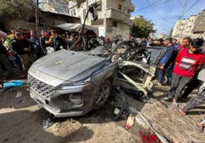 Palestinians inspect a car hit by an Israeli strike in Rafah