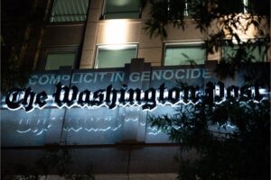 A projection declares the Washington Post “complicit in genocide” during a march for Gaza on a worldwide day of action for Palestine, October 12, 2023