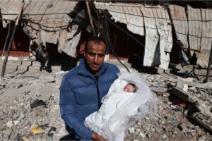 A man in Rafah poses for a picture with his newborn baby