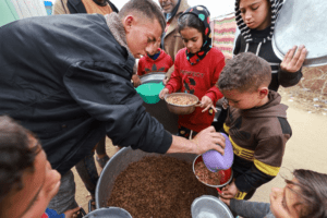 Palestinian children receive food cooked by a charity kitchen amid shortages of food supplies, in Rafah, in the southern Gaza Strip, on 13 February