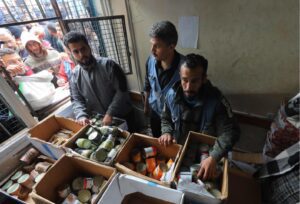 Displaced Palestinians in a UN-run school crowd around a window to receive canned goods in Deir al Balah in Gaza on January 29