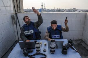 Palestinian journalists attempt to connect to the internet using their phones in Rafah, Gaza
