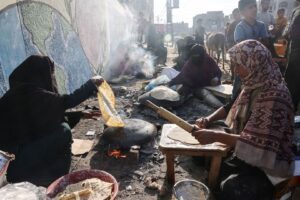 Women make traditional unleavened bread on an open fire at a shelter for displaced families mainly from northern Gaza, at a UN-run school in Rafah, in the south on October 27. Israel's complete blockade on the Palestinian enclave has triggered severe food shortages.