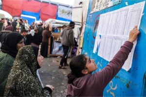 A girl checks a roster of names to receive bedding supplies from a refugee shelter in Rafah, Gaza