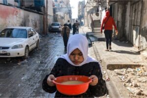 A girl carries a bowl of lentils along an alley in Rafah in the southern Gaza Strip on Tuesday