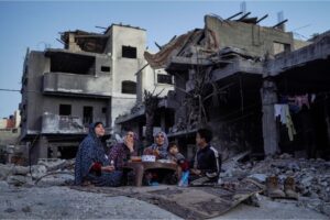 The Palestinian Al-Naji family eats an iftar meal, the breaking of fast, amid the ruins of their family house, on the first day of the Muslim holy fasting month of Ramadan, in Deir el-Balah on Monday