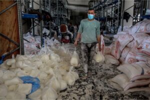 Volunteers and aid workers help to sort large bags of flour received into smaller bags in in Gaza City on Sunday