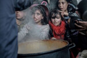 Palestinian children are seen as they wait in front of a boiler amid steam to receive hot food distributed by charitables and charity organization in Gaza City, Gaza on February 26, 2024.