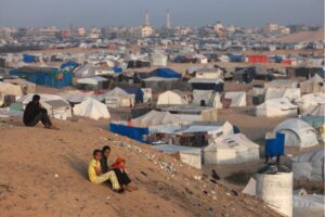 Palestinian children sit on a hill next to tents housing the displaced in Rafah in the southern Gaza Strip on 30 March, 2024