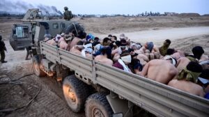 Israeli soldiers stand by a truck packed with shirtless Palestinian men and one woman in the besieged Gaza Strip on 8 December 2023