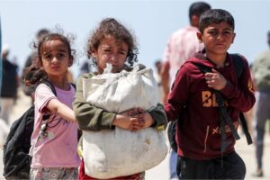 Children walk with other displaced Palestinians on the coastal al-Rashid Street to return to Gaza City