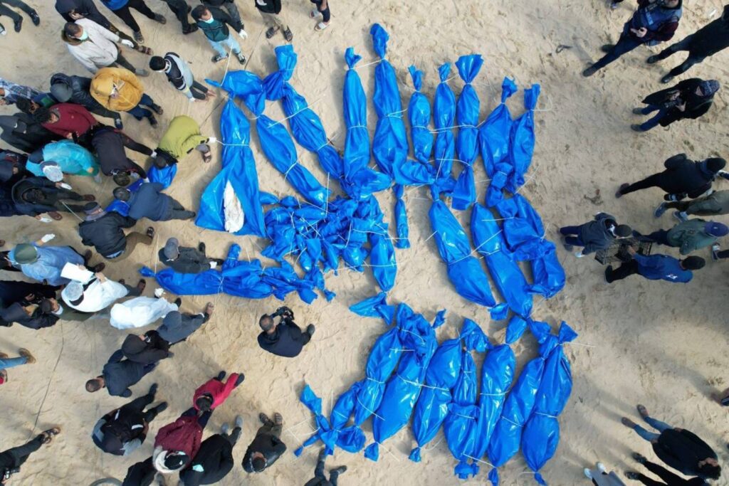 An aerial view of the dead Palestinian bodies that are confiscated by Israel were delivered through the Kerem Abu Salim border crossing and are buried in a mass grave dug in Rafah, Gaza on January 30, 2024 [Mohammed Fayq – Anadolu Agency]