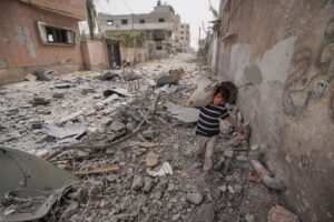 A Palestinian child carries a bag as he walks amidst the debris in Nuseirat refugee camp.
