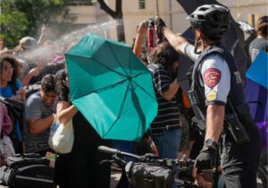 A state trooper on a bicycle pepper sprays pro-Palestinian protesters at the University of Texas in Austin