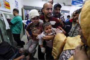 A man carries children wounded in Israeli bombardment at al-Najjar Hospital in Rafah