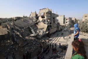 Palestinians stand on a rooftop overlooking the destruction in Rafah