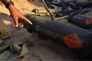 A Palestinian man points to US military markings on a discarded ammunition container