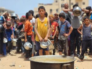 Palestinian children queue with their containers for food at Rafah’s last remaining food distribution center. [Hani Alshaer/Anadolu]