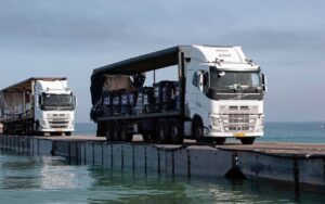Trucks loaded with humanitarian aid from the United Arab Emirates and the United States Agency for International Development cross the Trident Pier before entering the beach in Gaza, May 17, 2024.