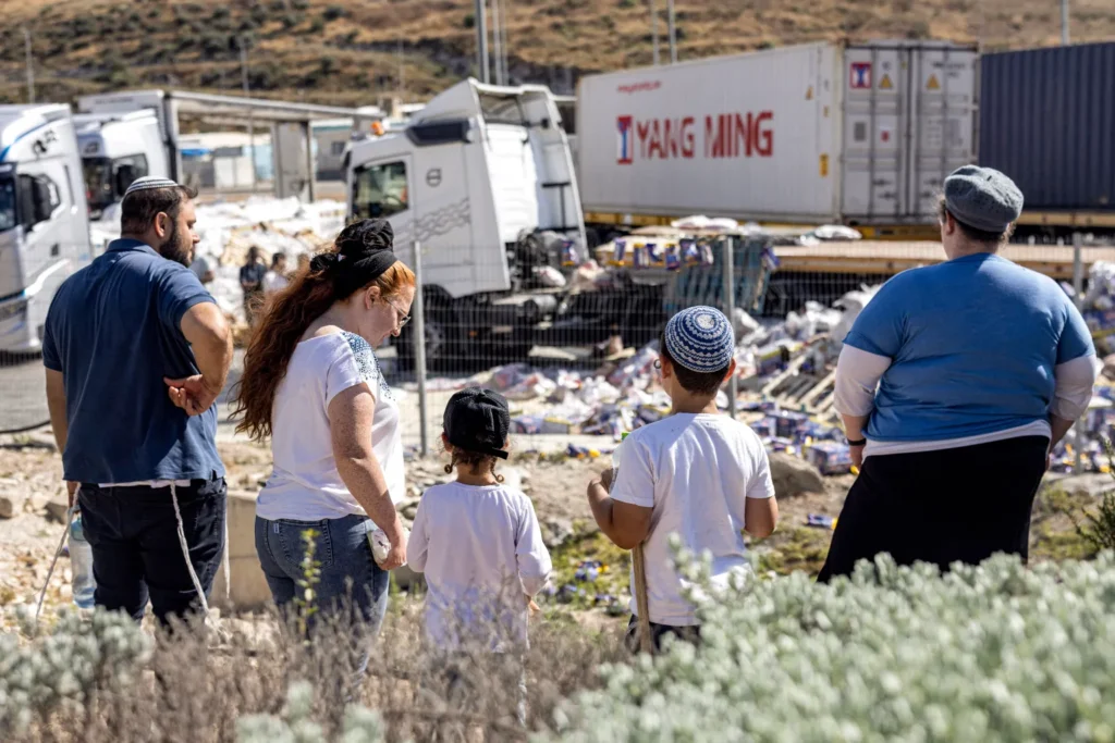 Israeli right-wing activists look at damaged trailer trucks that were carrying humanitarian aid supplies on the Israeli side of the Tarqumiyah crossing with the occupied West Bank on May 13, 2024, after they were vandalized by other activists to protest aid being sent to the Gaza Strip.