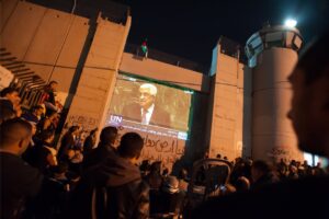 Palestinians gather to watch the speech by President Mahmoud Abbas in the bid for Palestine’s “non-member observer state” status at the United Nations, projected on the Israeli separation wall in the West Bank town of Bethlehem, November 29, 2012.