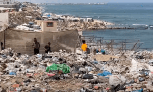 Children walk through accumulated trash near the beach, Deir al Balah, Gaza