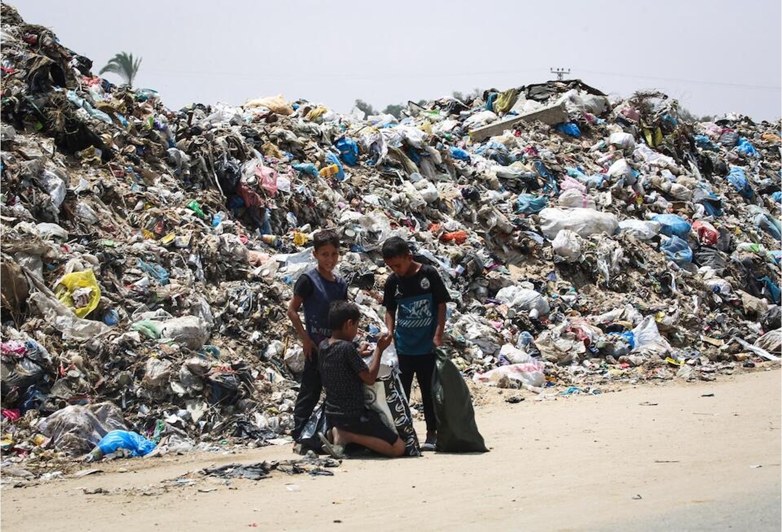 Children stand beside piles of waste growing alongside the tents of displaced people in Rafah, southern Gaza Strip. Inadequate sanitation poses a grave risk to children's health and well-being.