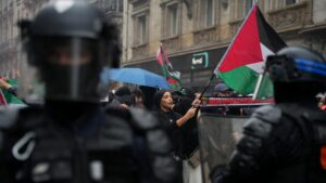 A protester waves a Palestinian flag facing French riot police officers during a rally in central Paris on 29 May 2024
