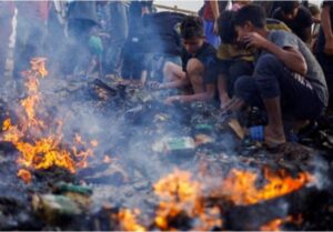 Palestinians search for food among burnt debris in the aftermath of an Israeli strike on an area designated for displaced people, in Rafah in the southern Gaza Strip, May 27, 2024.