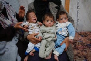 Palestinian triplets with their mother flee following the Israeli army’s attacks on Shifa Hospital in Gaza City, Gaza on March 21, 2024 [Ashraf Amra/Anadolu Agency]