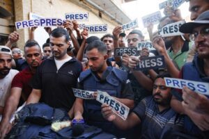 Anas al-Sharif (center) and mourners holding “press” signs surround the body of Al Jazeera Arabic journalist Ismail al-Ghoul, killed along with his cameraman Rami al-Refee in an Israeli strike on July 31, 2024. Photo by Omar Al-Qattaa/AFP via Getty Images.