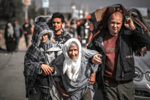 Palestinians assist an elderly woman while fleeing the Israeli military attack on northern Gaza - 10 November 2023, (Bilal Khaled/Anadolu/Getty Images)